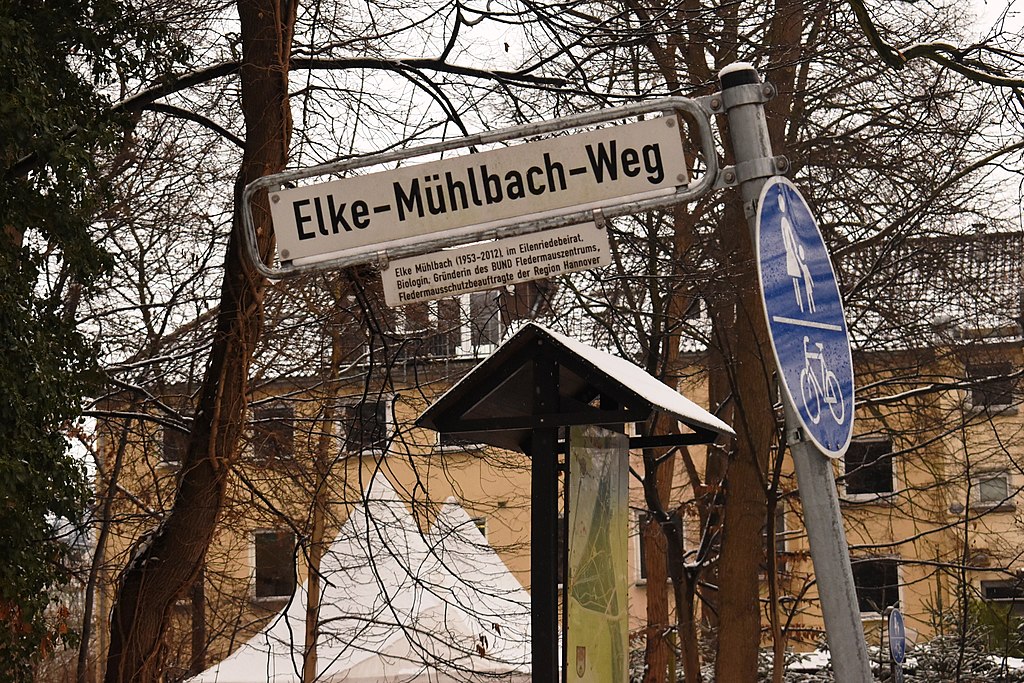 Straßenschild mit Legendentafel am Elke-Mühlbach-Weg in der Eilenriede in Hannover-Waldhausen: „Elke Mühlbach (1953-2012) im Eilenriedebeirat, Biologin, Gründerin des BUND Fledermauszentrums, Fledermausschutzbeauftragte der Region Hannover“