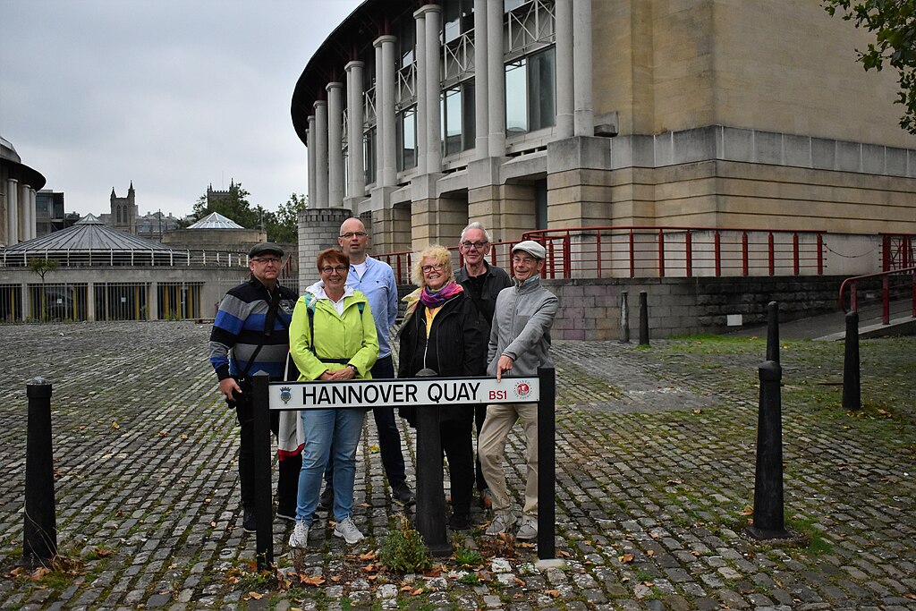Das Team von Wikipedia Hannover hat sich auf seiner Exkursion in Hannovers Partnerstadt Bristol zum Gruppenfoto hinter dem Straßenschild 'Hannover Quay' versammelt.