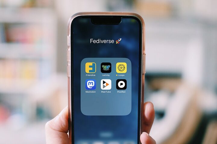 Ein Foto von einem Smartphone, das in einer Hand gehalten wird; auf dem Bildschirm sieht man Symbole von Fediverse Apps: Lemmy, Loops, Mastodon, PeerTube und Pixelfed.