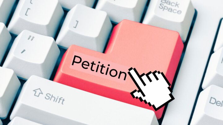 Die Grafik zeigt eine weiße Computertastatur, deren Enter-Taste lachsfarben hervorgeboben steht. Darauf stehe das Wort Petition und eine Hand mit ausgestrecktem Zeigefinger schwebt über der Taste, wie kurz vor dem Klick. Grafik: Erstellt mit Canva