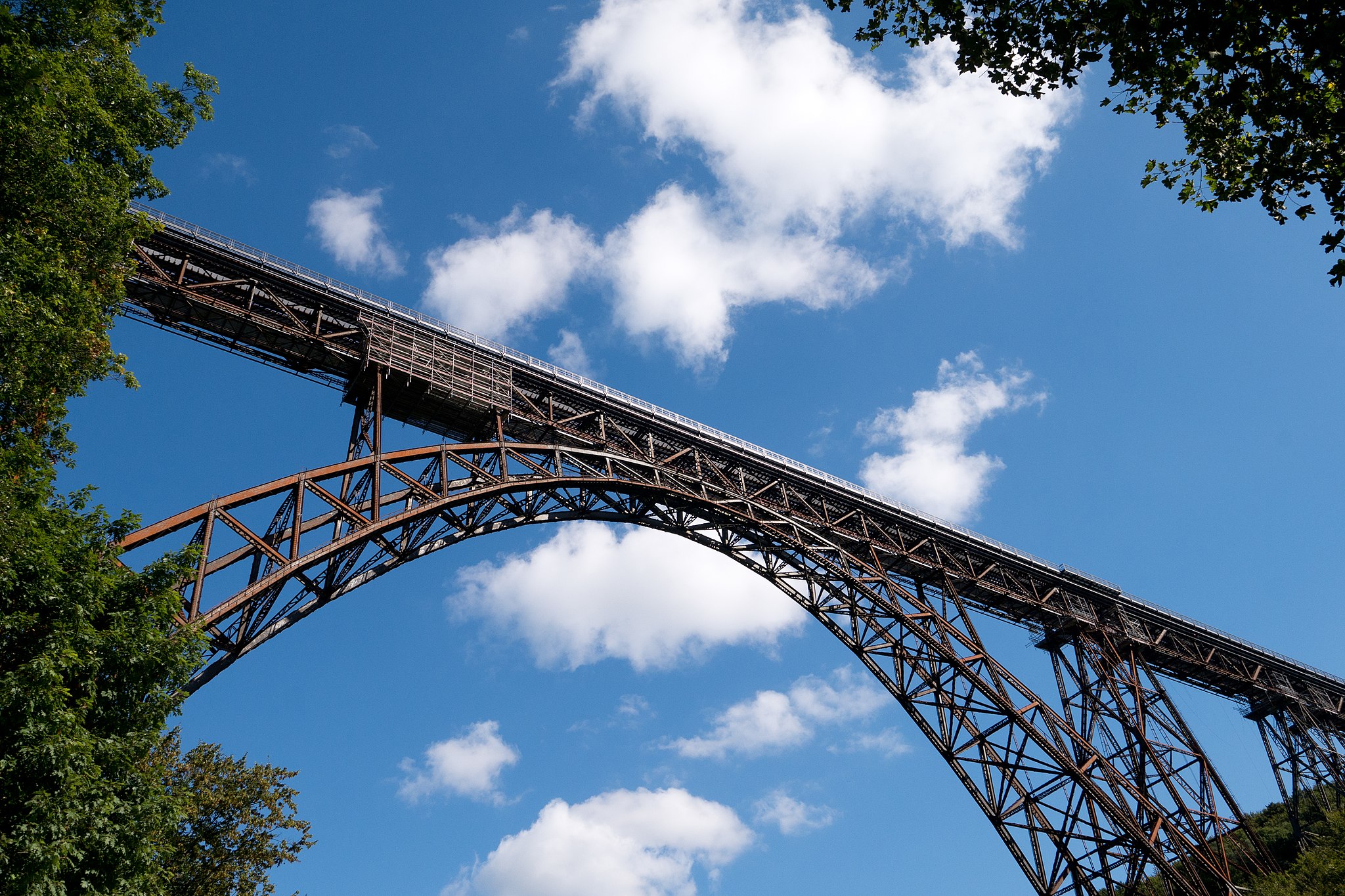 Die Müngstener Brücke, fotografiert von unten mit Blick auf einen blauen Himmel an einem sonnigen Tag.
