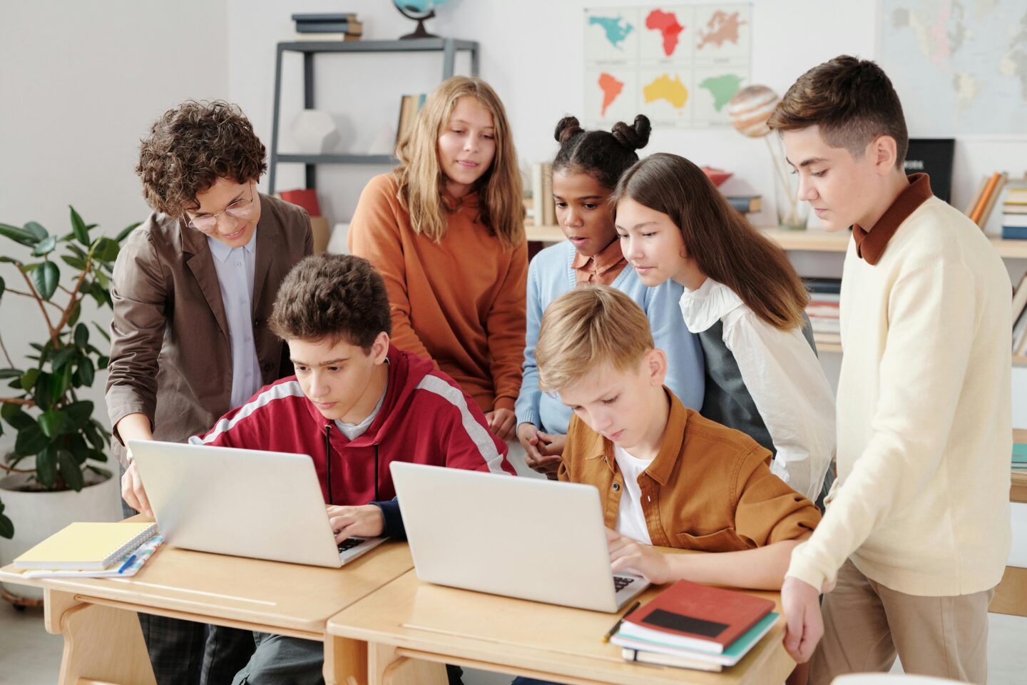 Eine Gruppe von Kindern schaut gemeinsam auf die Bildschirme eines Laptops in der Schule.