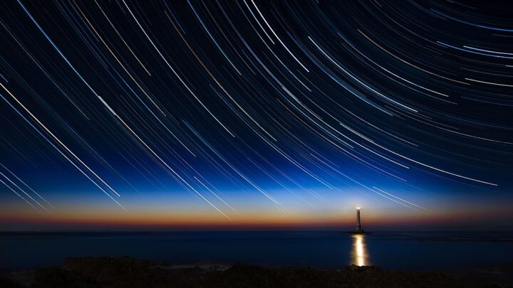 Eine über zwei Stunden belichtete Fotografie von zirkumpolaren Sternen, die als Spuren am Leuchtturm von La Hague in der Normandie (Frankreich) zu sehen sind.