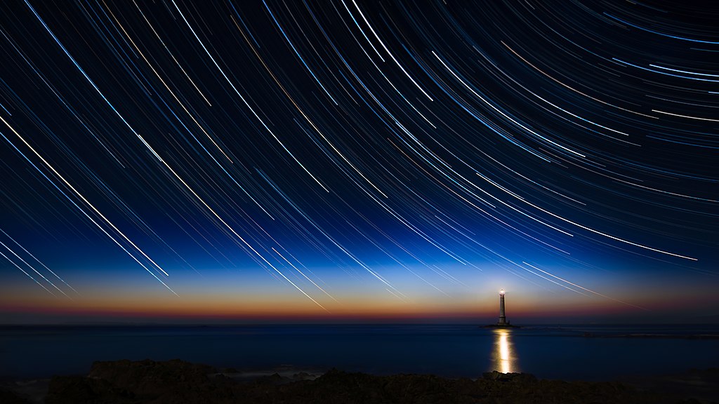 Eine über zwei Stunden belichtete Fotografie von zirkumpolaren Sternen, die als Spuren am Leuchtturm von La Hague in der Normandie (Frankreich) zu sehen sind.