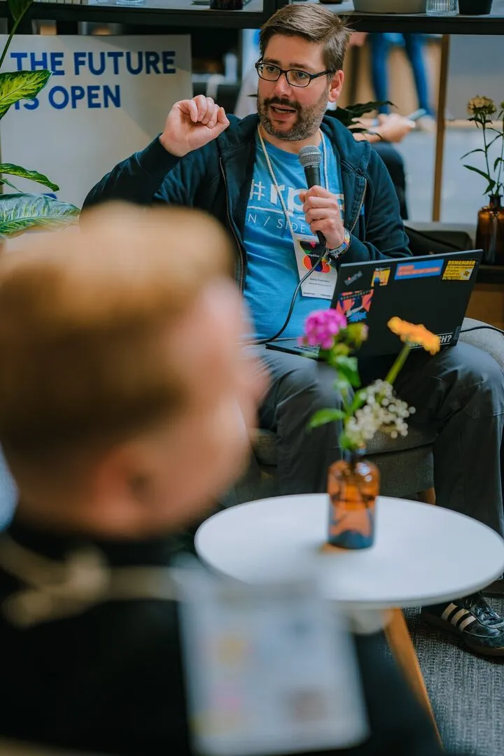 Das Foto zeigt Stefan Kaufmann, Referent Politik und öffentlicher Sektor bei Wikimedia Deutschland, der mit Mikorofon in der Hand auf dem Sofa an unserem Stand bei der Republica 2025 sitzt. Stefan spricht gerade über irgendetwas mit Daten. Genauer gesagt: Warum Verwaltungen in Deutschland auf regelbasierte KI setzen sollten statt auf generative Modelle wie Chatbots.