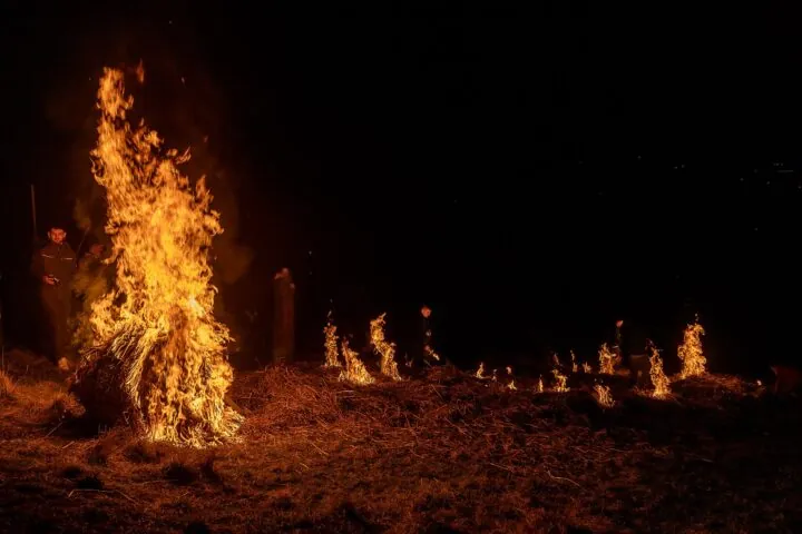 Winteraustreibung "Schewe Sunnesch" in Gees (Gerolstein). Ein mit Stroh gefülltes Rad wird brennend den Berg hinabgerollt. Vor dem brennenden Rad wird eine Bahn aus Stroh ebenfalls in Brand gesetzt.