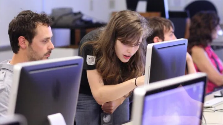 Zwei Personen schauen gemeinsam auf einen PC.