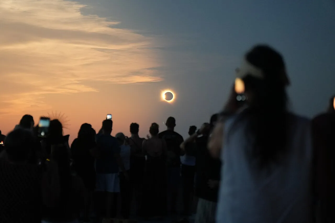 Menschenmenge fotografiert Sonnenfinsternis am Himmel.