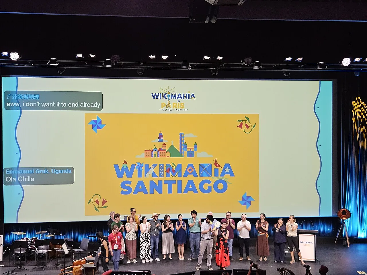 Menschen auf einer Bühne, im Hintergrund der Schriftzug: "Wikimania Santiago".