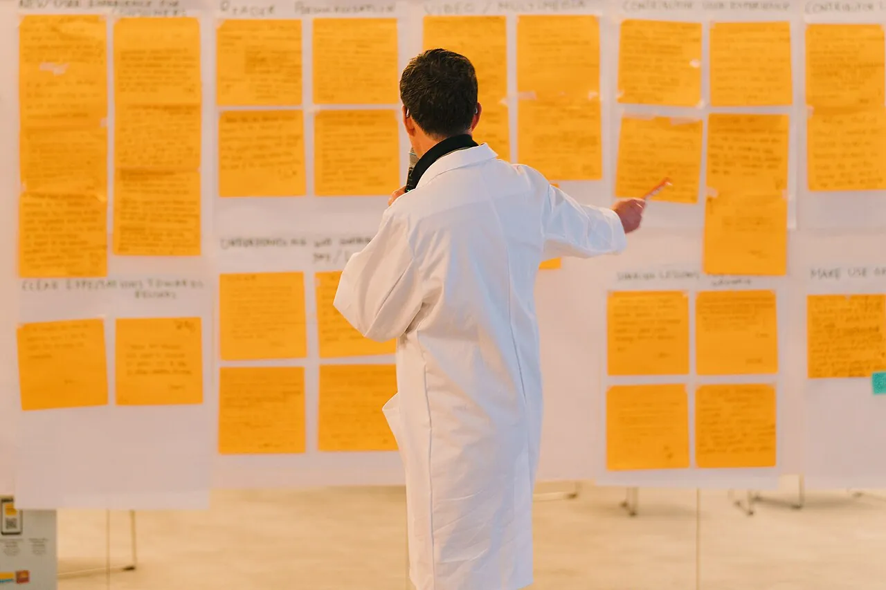 Person steht vor einer Wand mit vielen großen Notizzetteln